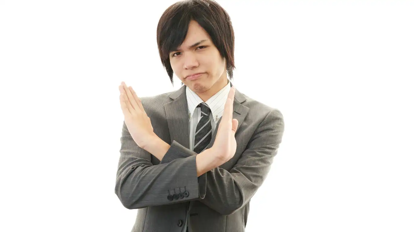 両手でバツ印をしたスーツ姿の男性