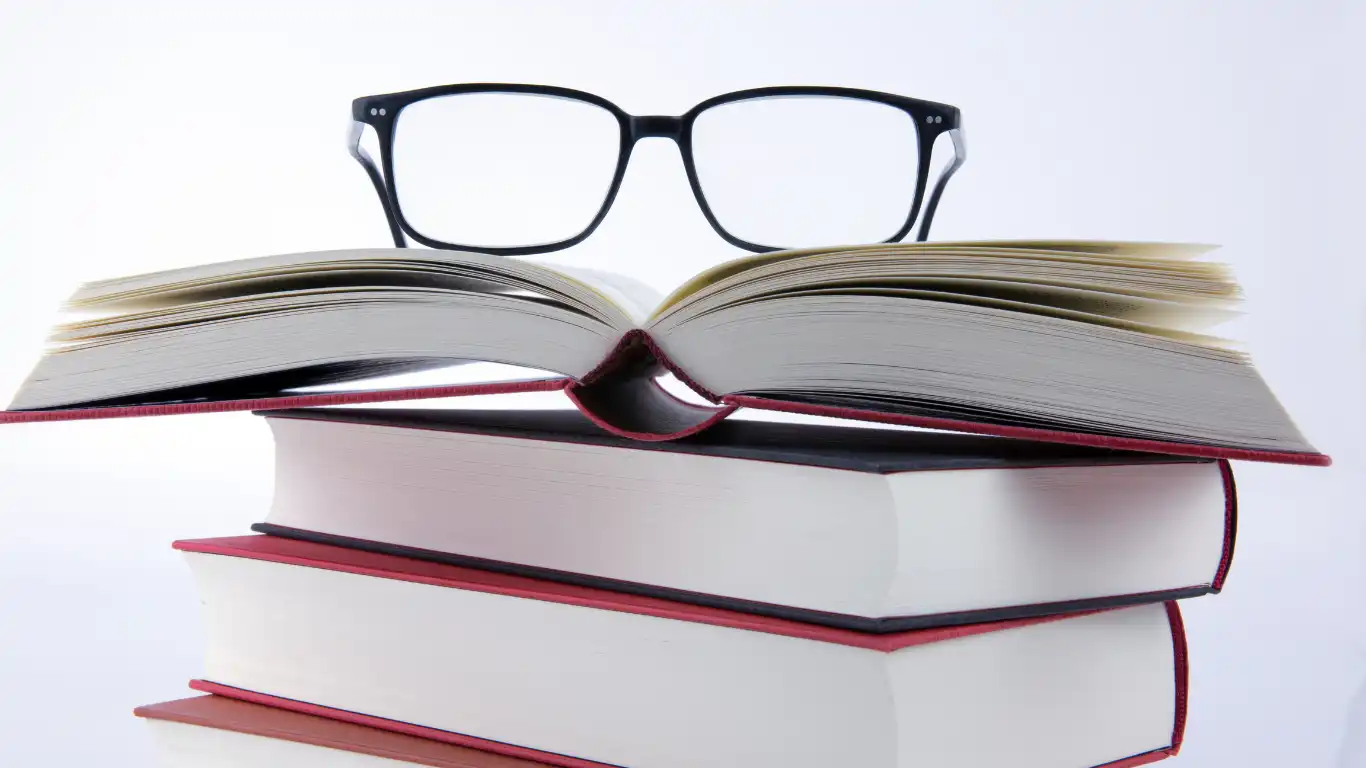 分厚い本4冊の上にメガネが置かれている