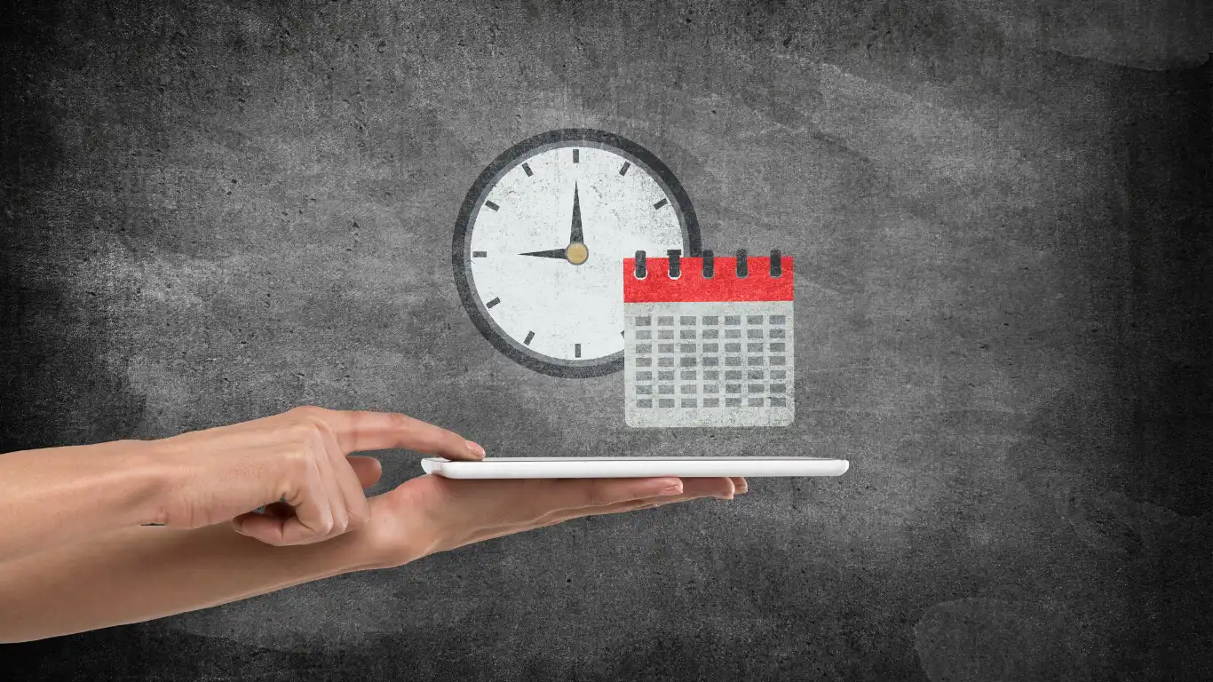 時計を掛けてある壁の前でカレンダーを持っている