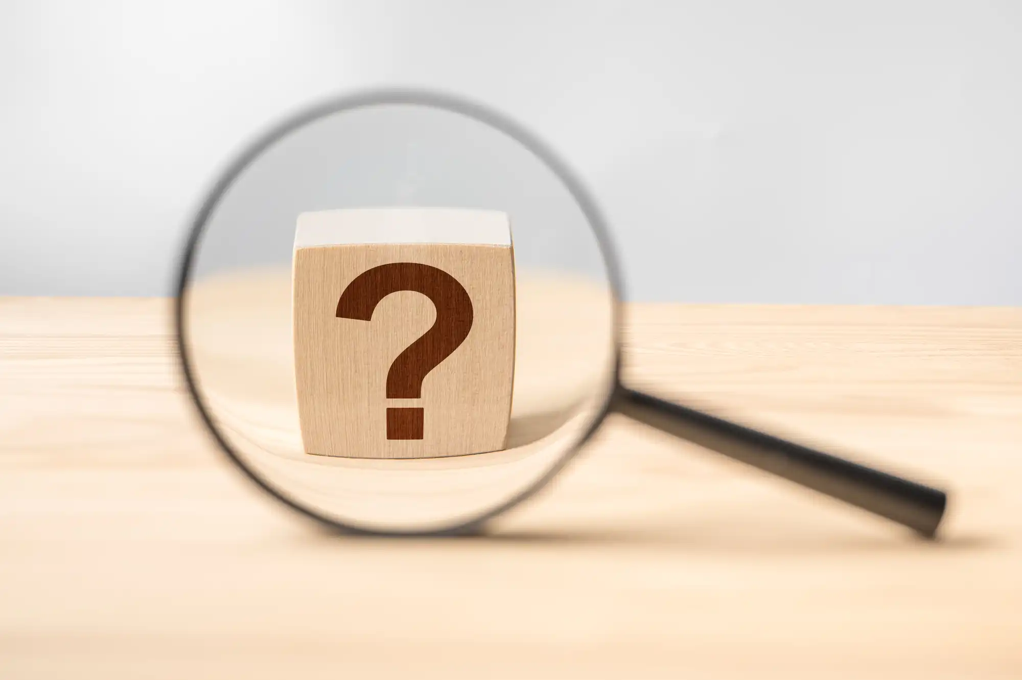 ？と書かれた積み木を虫眼鏡で見ている