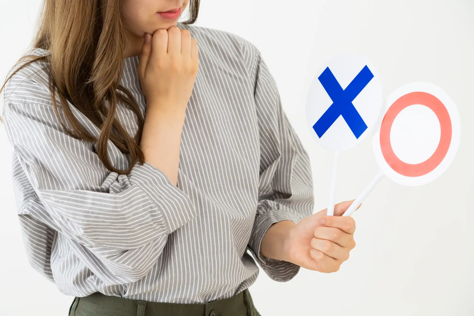 グレーの服を着た女性が◯か×で迷っている